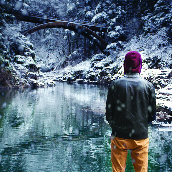 Person in jacket standing in front of a snow covered Moulton Falls Bridge